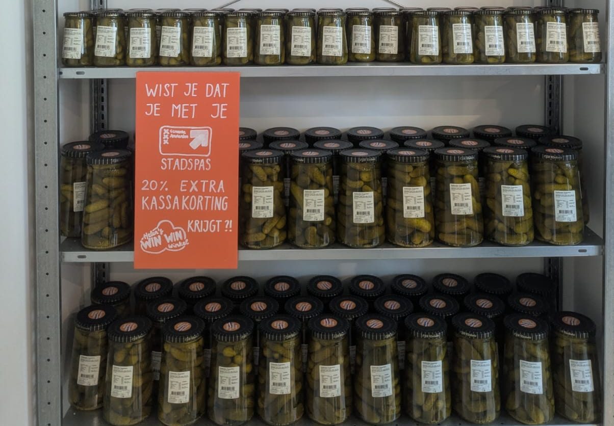 Een schap vol potten Kesbeke-augurken in de winkel, met het bord over 20% extra korting met de Stadspas